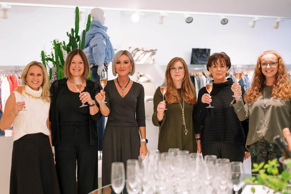 Eine Gruppe von Frauen steht nebeneinander und hält Weingläser in den Händen.