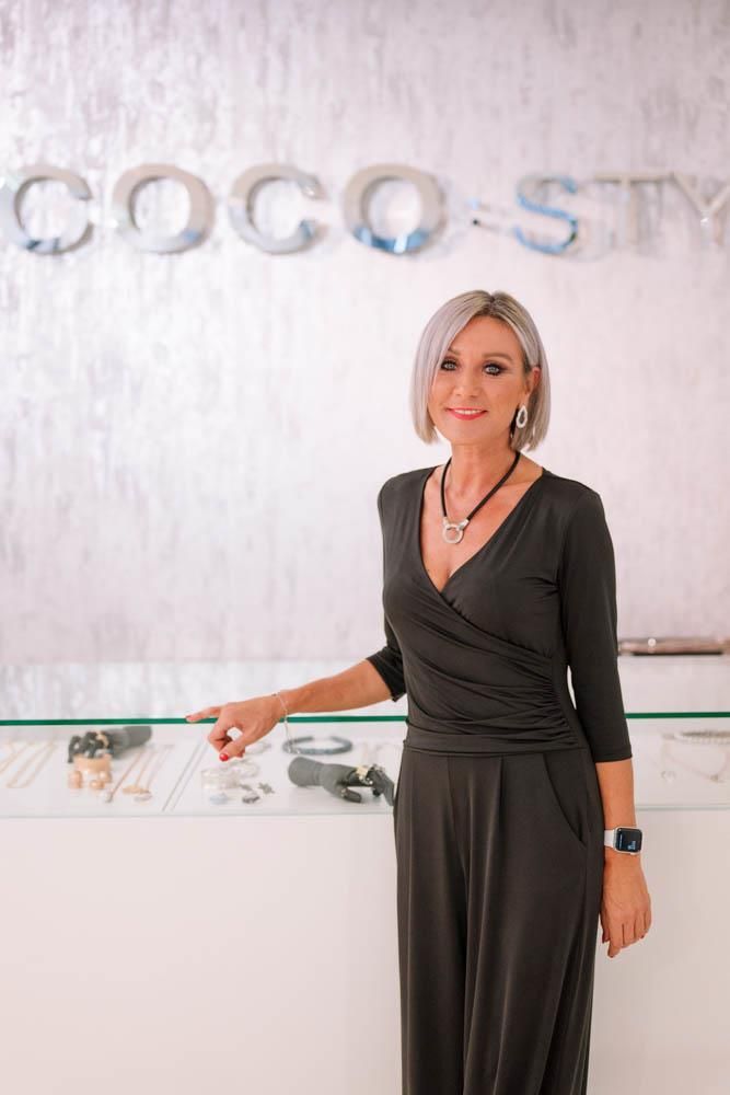 Eine Frau in einem schwarzen Kleid steht vor einer Vitrine in einem Geschäft.