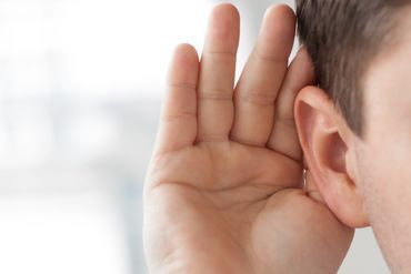 Person hält sich die Hand ans Ohr