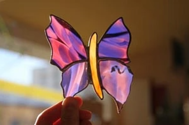 Une personne tient un papillon en vitrail dans sa main