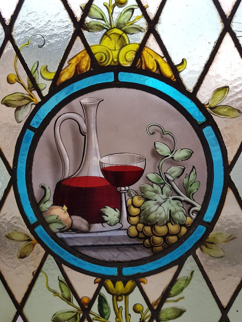Un vitrail montre une cruche de vin et un verre de vin
