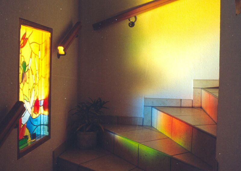 Un escalier avec un vitrail sur le mur
