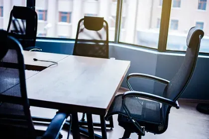 Una sala de conferencias con una mesa y sillas frente a una ventana.