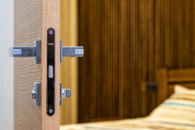 Una persona utiliza un destornillador para instalar o reparar un pomo de puerta plateado en una puerta de madera.