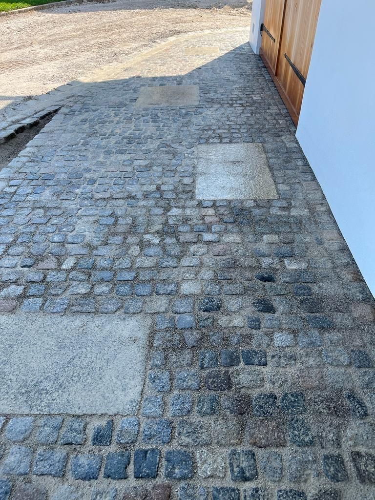 Ein Kopfsteinpflasterweg neben einem Gebäude mit einer Holztür.