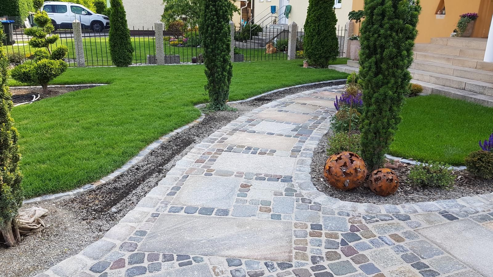 Ein Steinweg führt zu einem Haus in einem üppig grünen Garten.