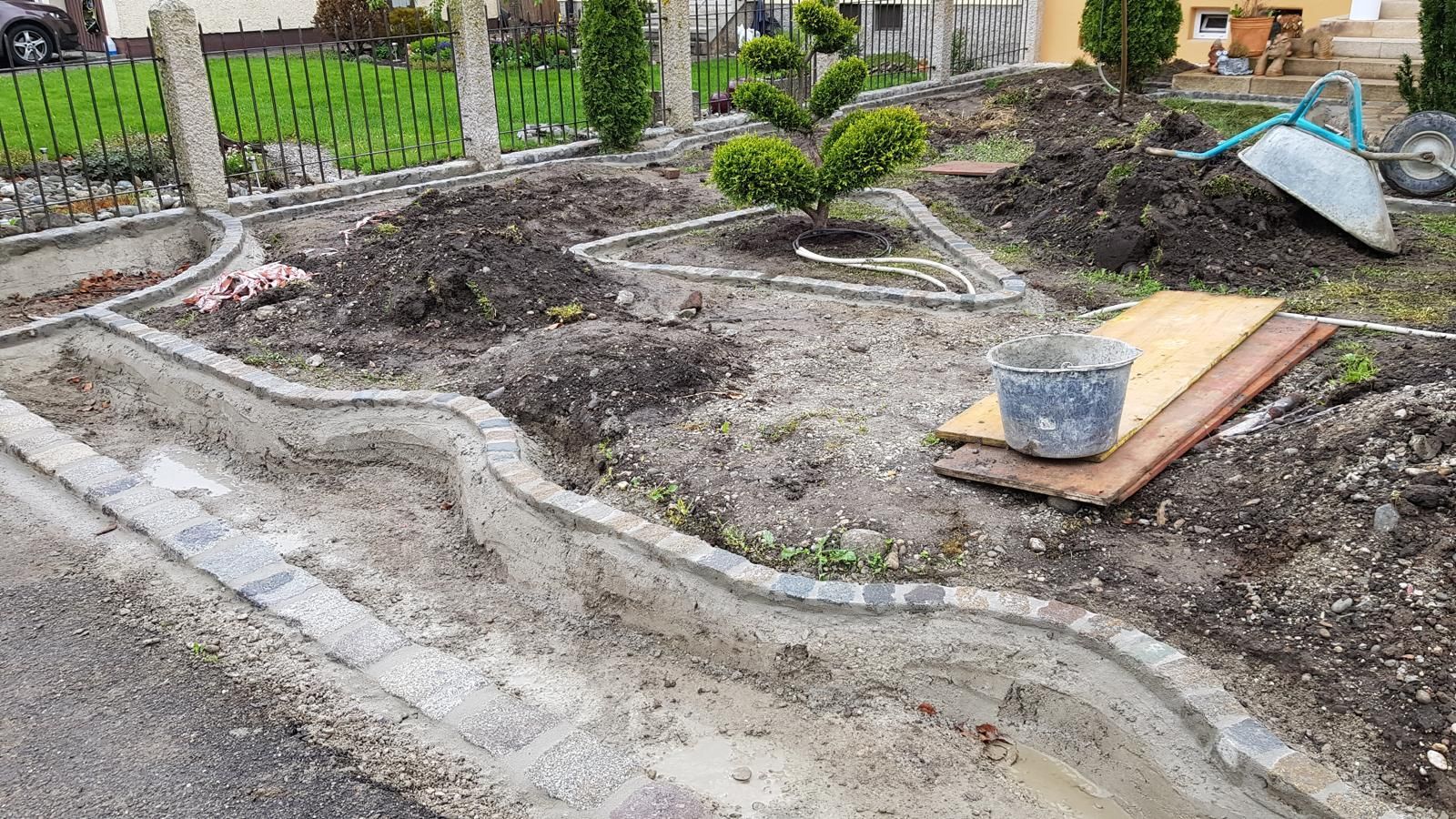 Eine Schubkarre steht auf einem Erdhaufen in einem Garten.