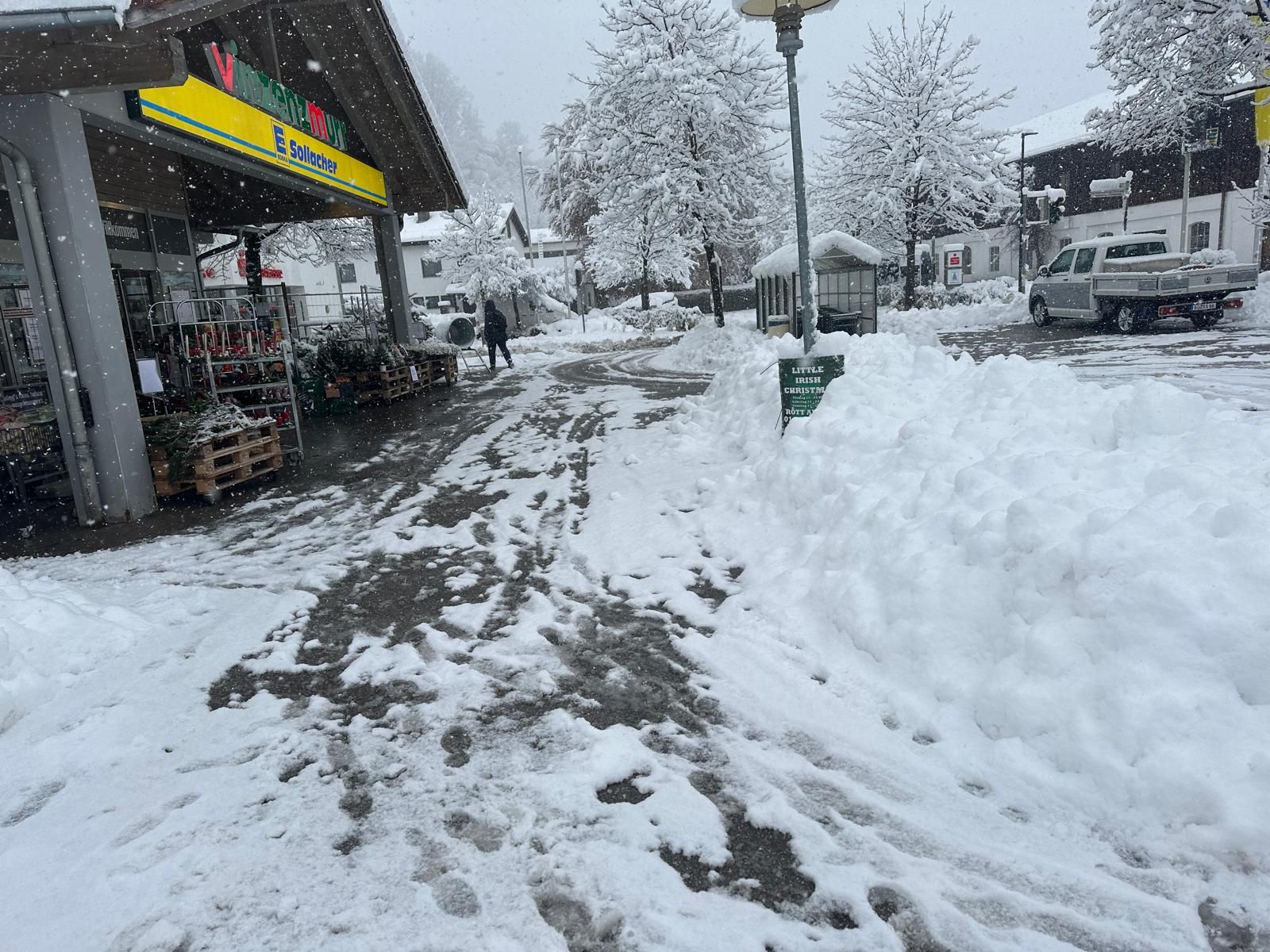 Eine verschneite Straße mit einem Geschäft im Hintergrund.