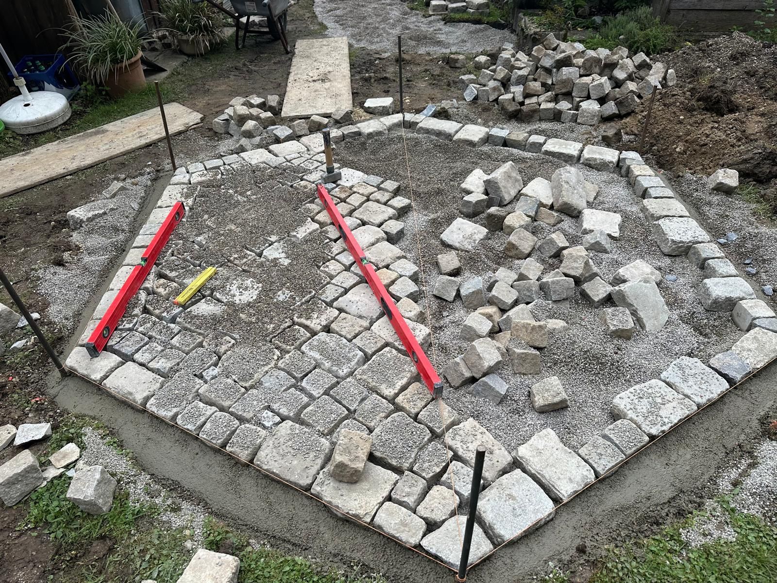 In einem Garten wird ein Stapel Ziegelsteine aufgebaut.