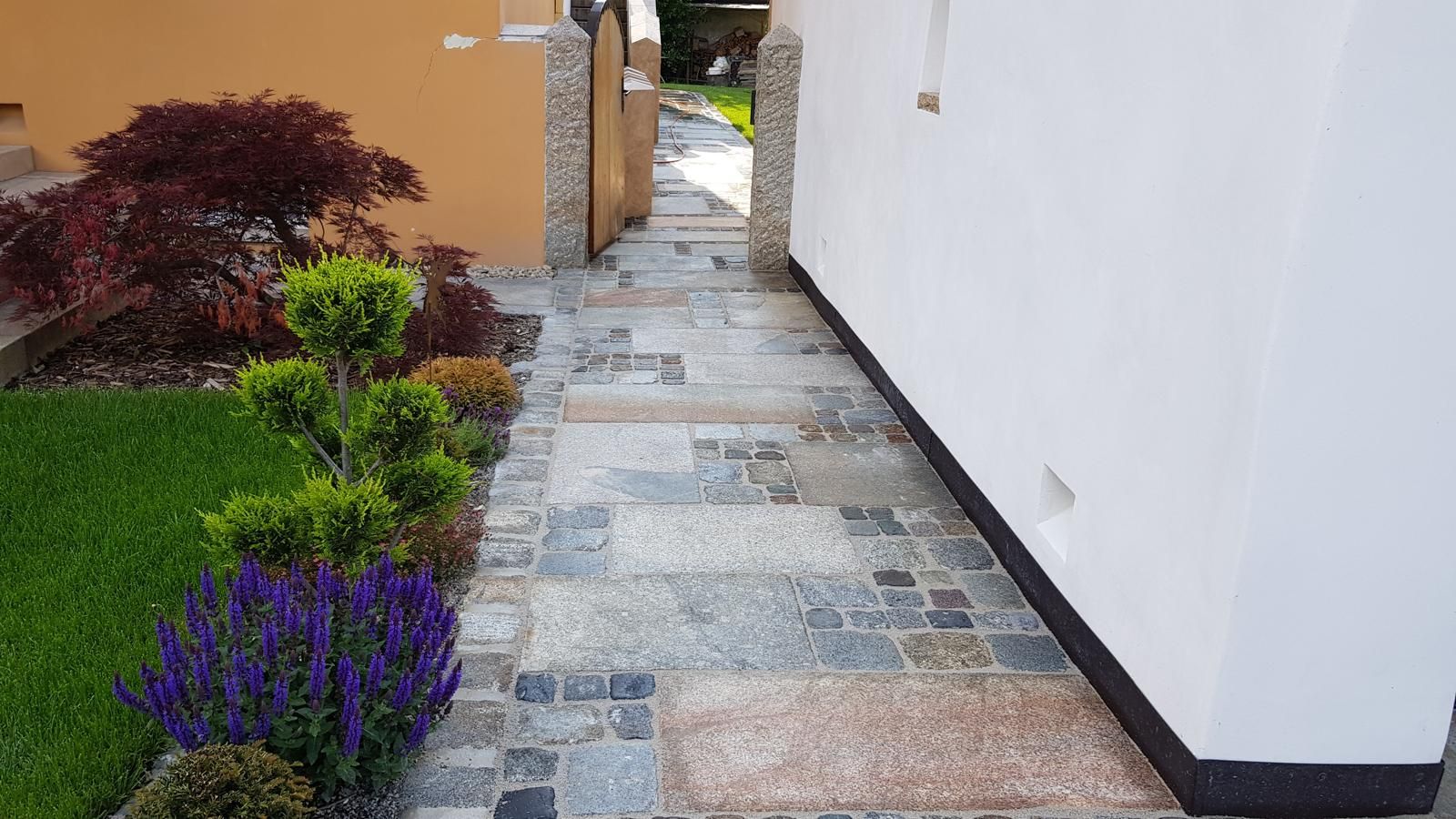 Ein Steinweg führt zu einem Haus mit Blumen an der Seite.