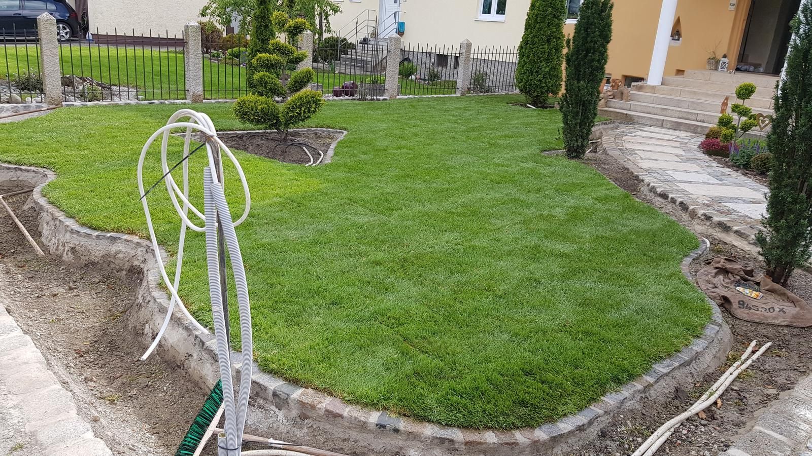 Vor einem Haus wird ein üppig grüner Rasen angelegt.