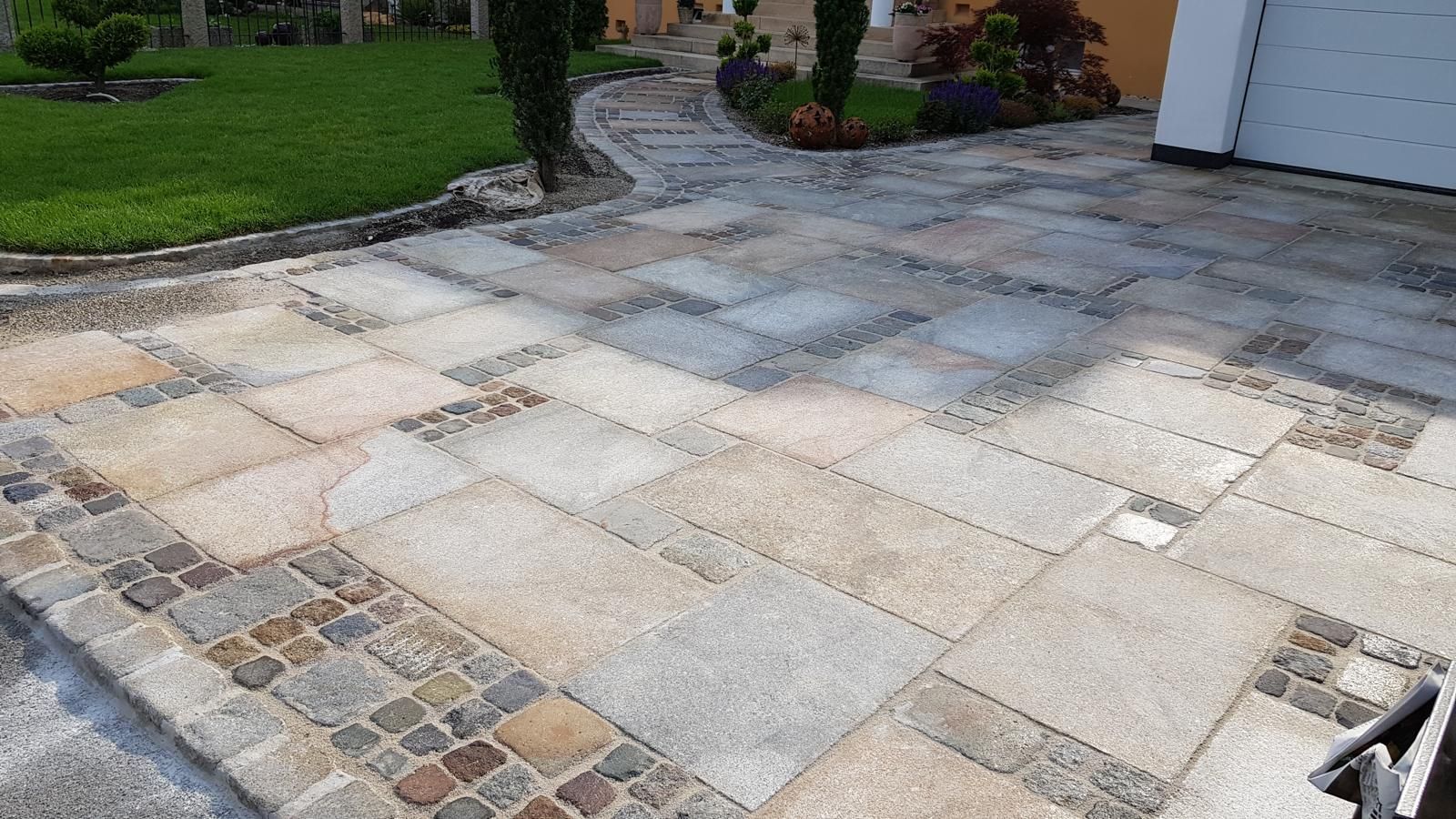 Eine Auffahrt mit einem gepflasterten Weg, der zu einer Garage führt.