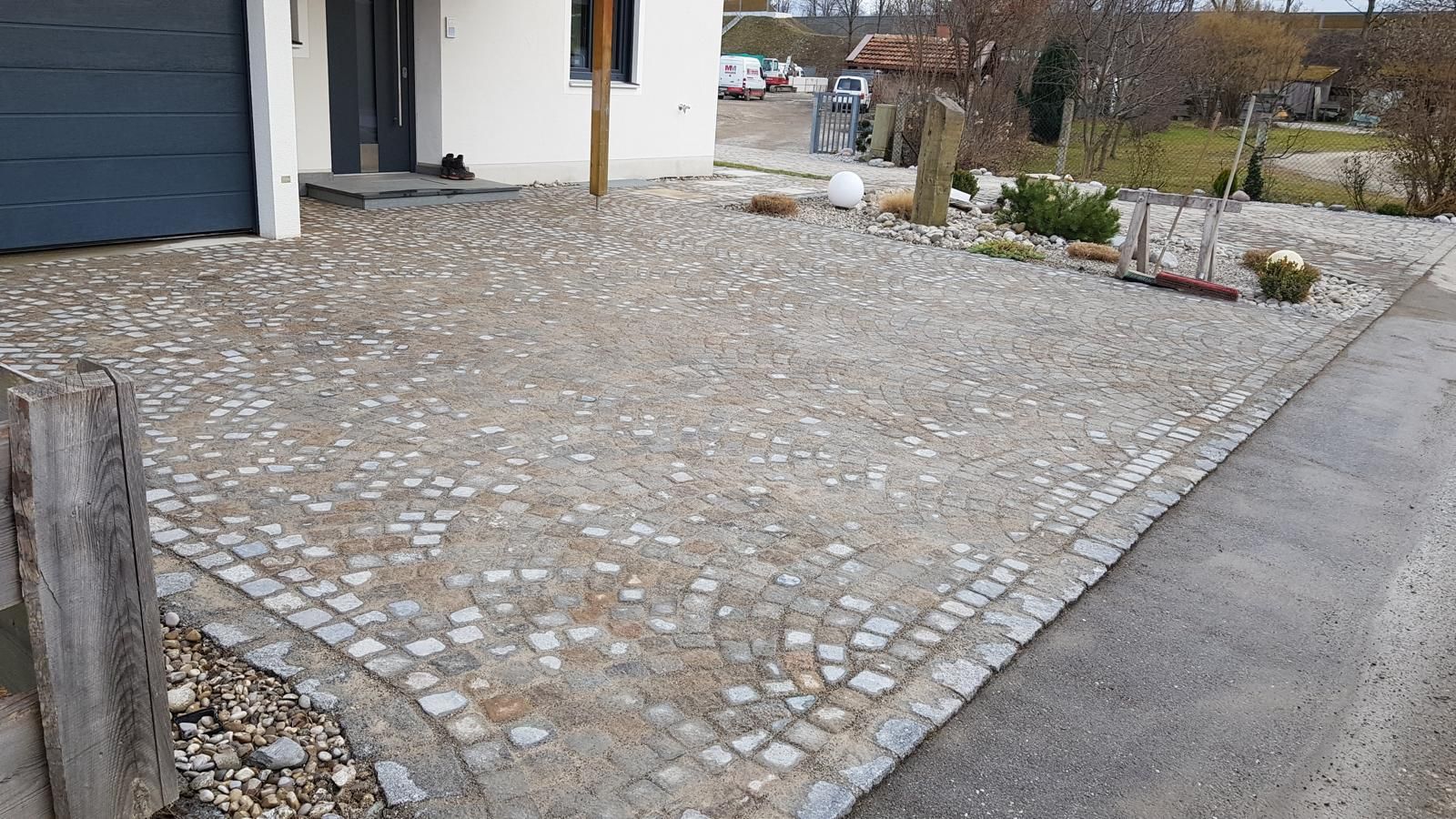 Eine gepflasterte Auffahrt vor einem Haus mit einem Garagentor.