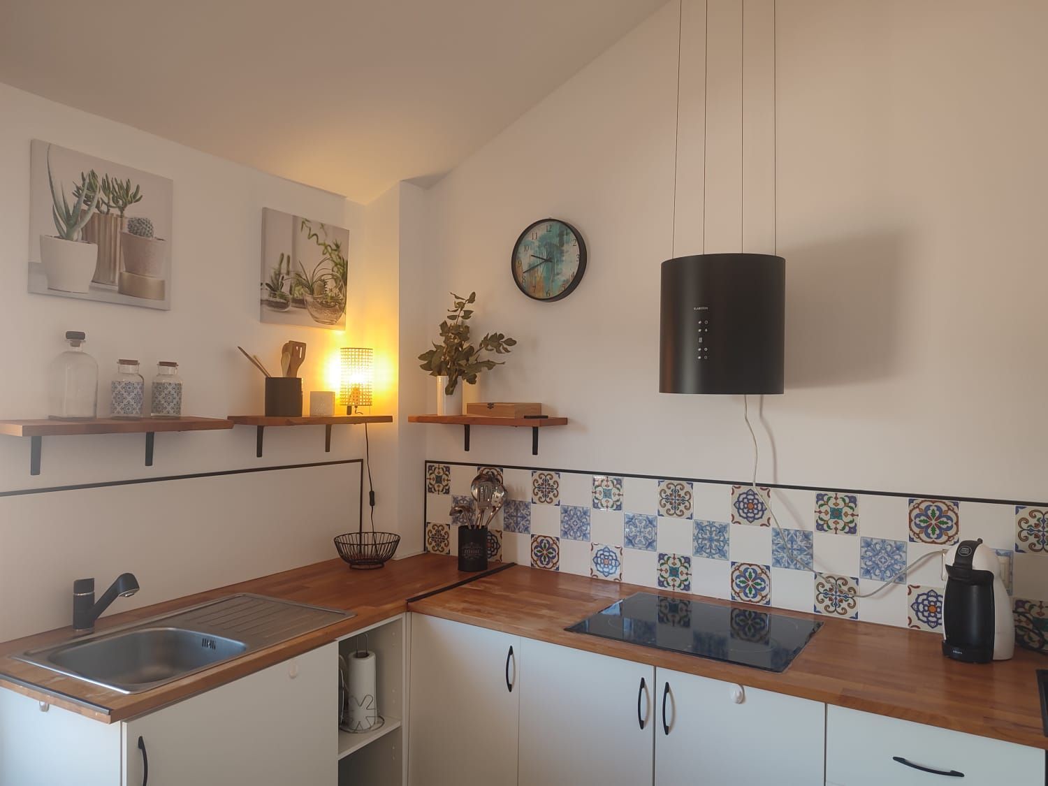 Una cocina luminosa con armarios blancos, encimeras de madera, salpicadero de azulejos estampados en azul y blanco