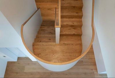 Draufsicht auf eine Holztreppe mit geschwungenen weissen Wänden und einem hellen Holzboden darunter