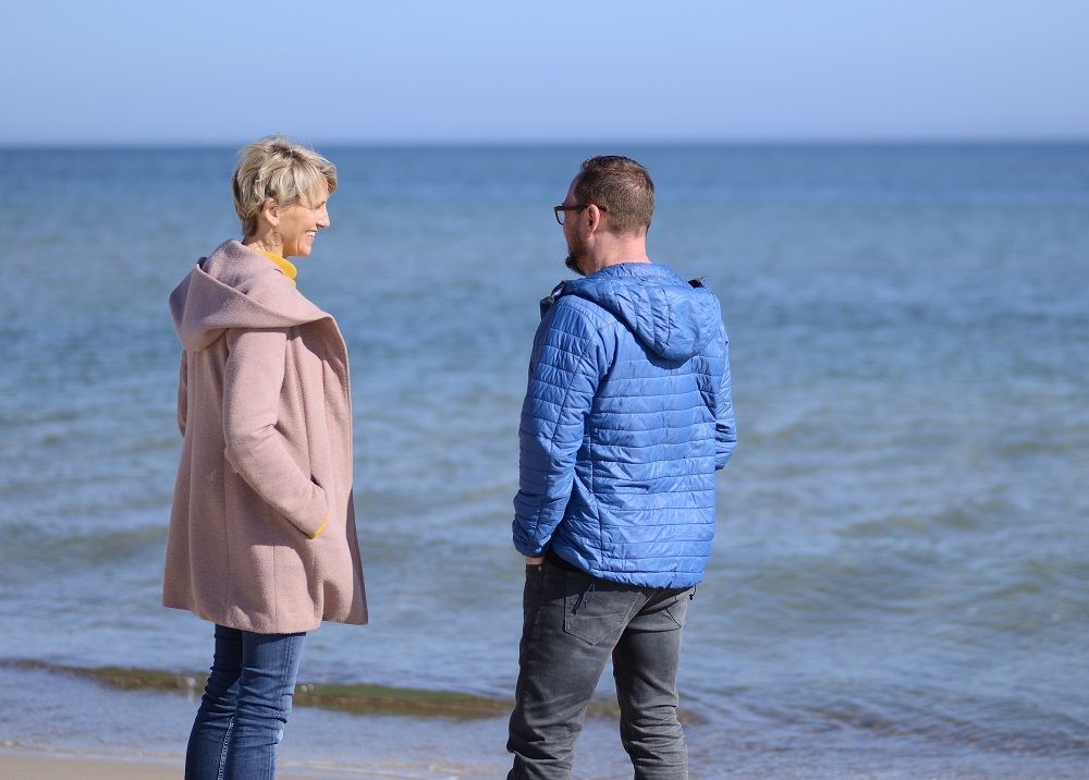Zwei Personen stehen sich am Strand gegenüber.