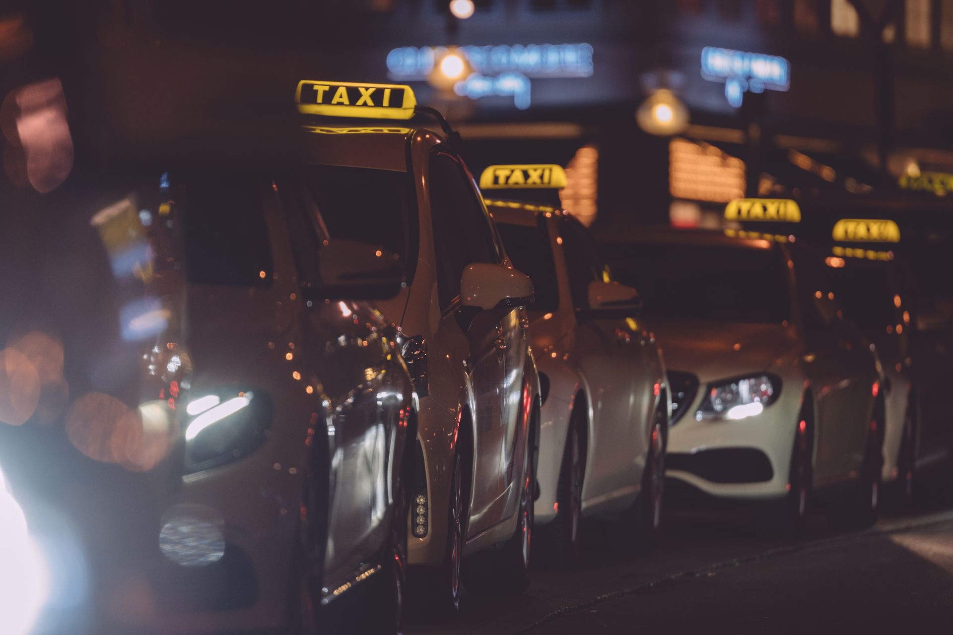 Eine Reihe von Taxis parkt nachts am Straßenrand.