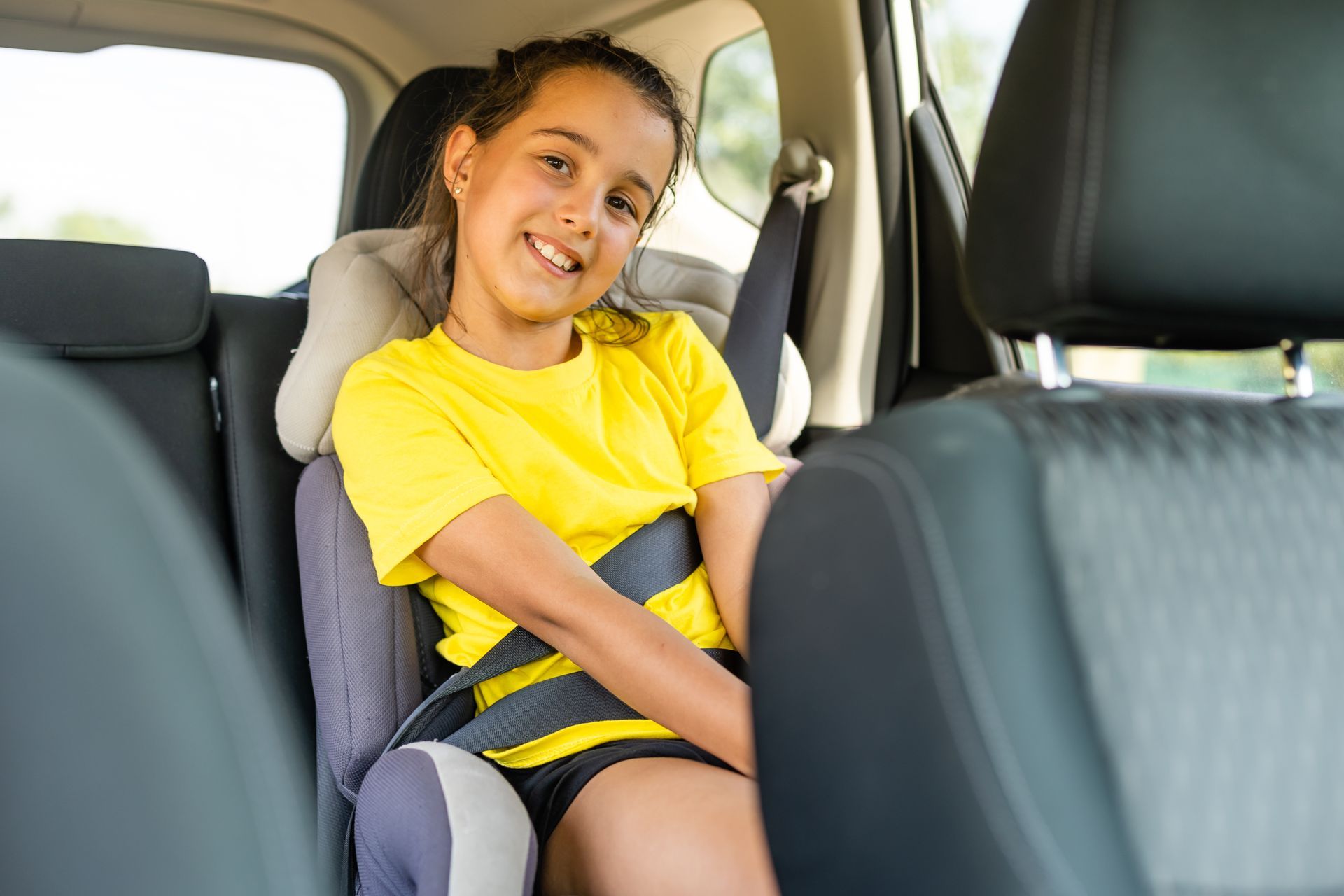 Kind sitzt auf einem Kidersitz, angeschnallt im Taxi