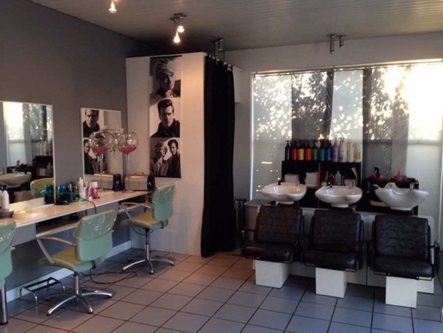 Intérieur du salon, espace avec bacs à shampoing et fauteuils noirs