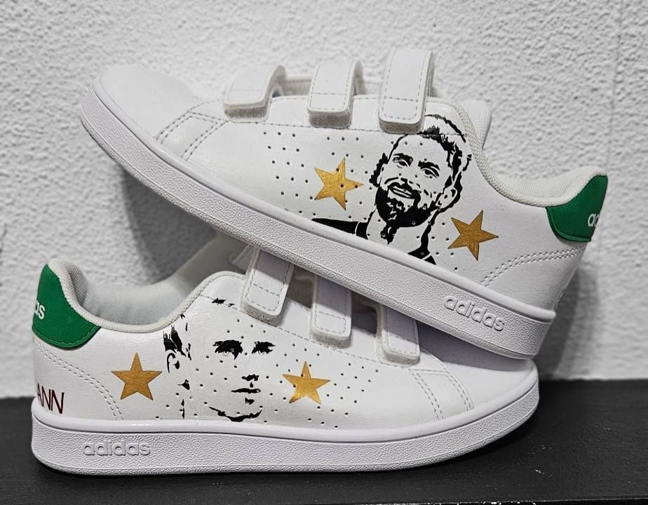 Baskets Adidas blanches avec portraits peints et étoiles dorées.