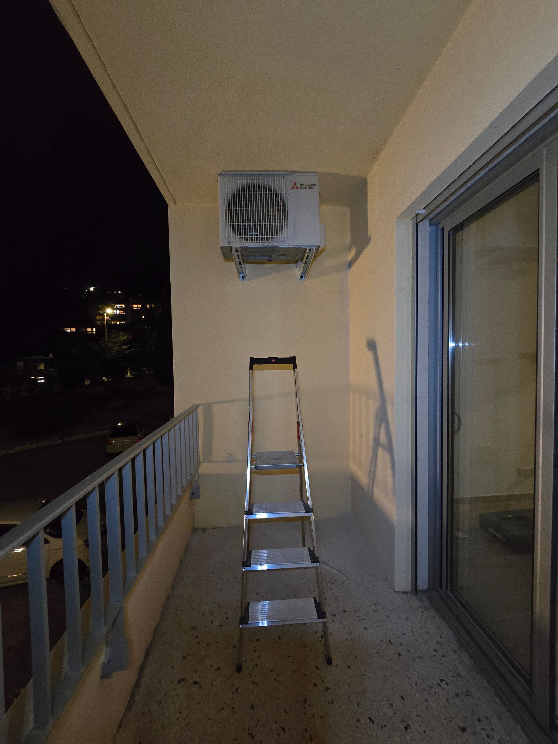 Balcon avec une échelle sous un climatiseur mural la nuit