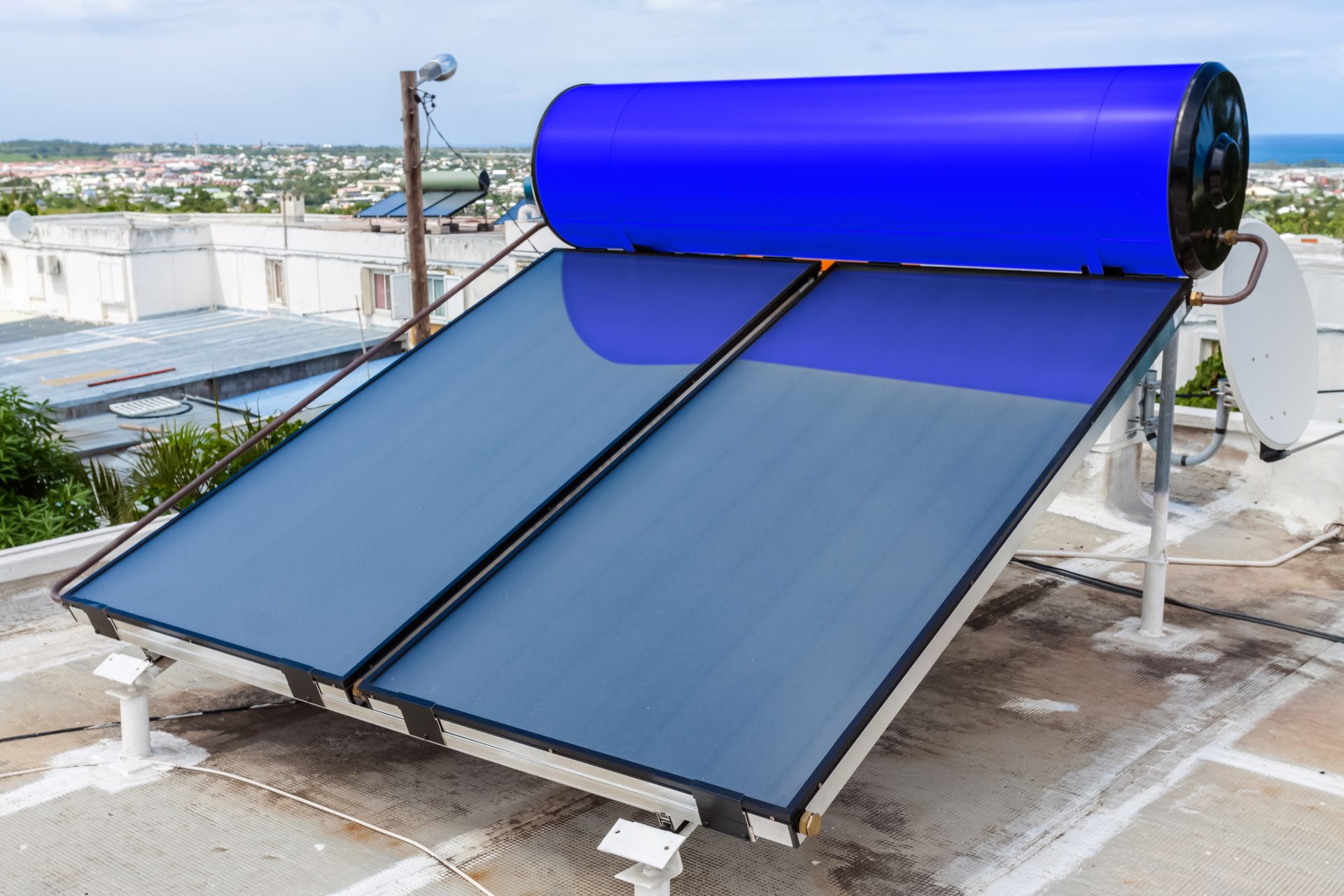 Chauffe-eau solaire avec panneaux bleus et réservoir sur un toit sous un ciel dégagé