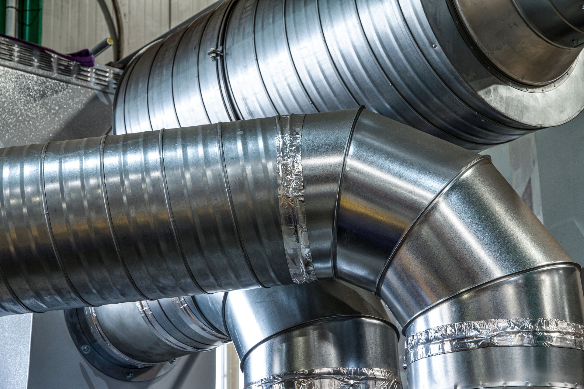 Conduits de ventilation en métal argenté brillant avec joints et coudes dans un environnement industriel