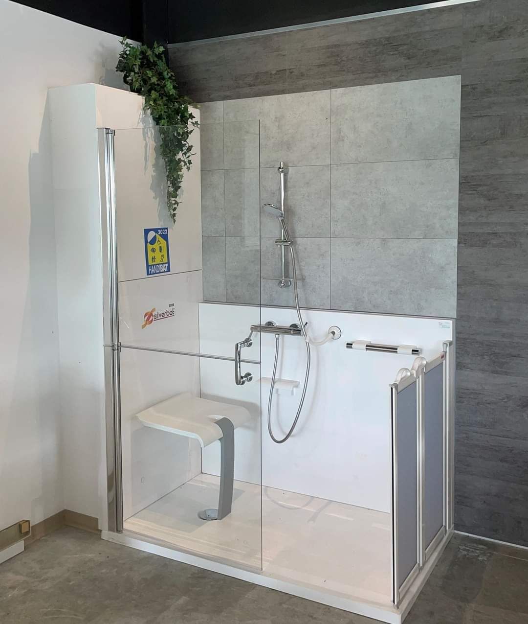 Salle de bains accessible avec douche et toilettes, robinetterie blanche, barres d'appui et meuble-lavabo
