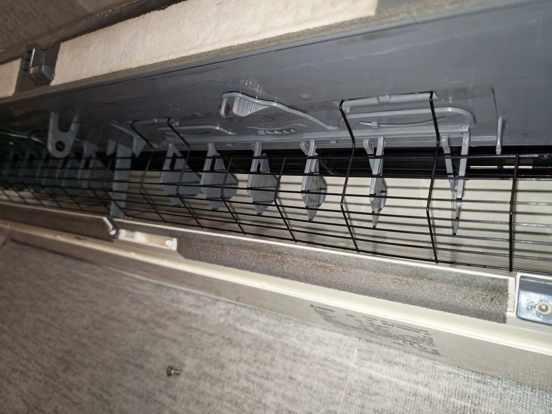 Gros plan sur un ensemble de ventilation ou de filtration métallique avec des fils et des clips de suspension à l'intérieur d'une fente étroite.