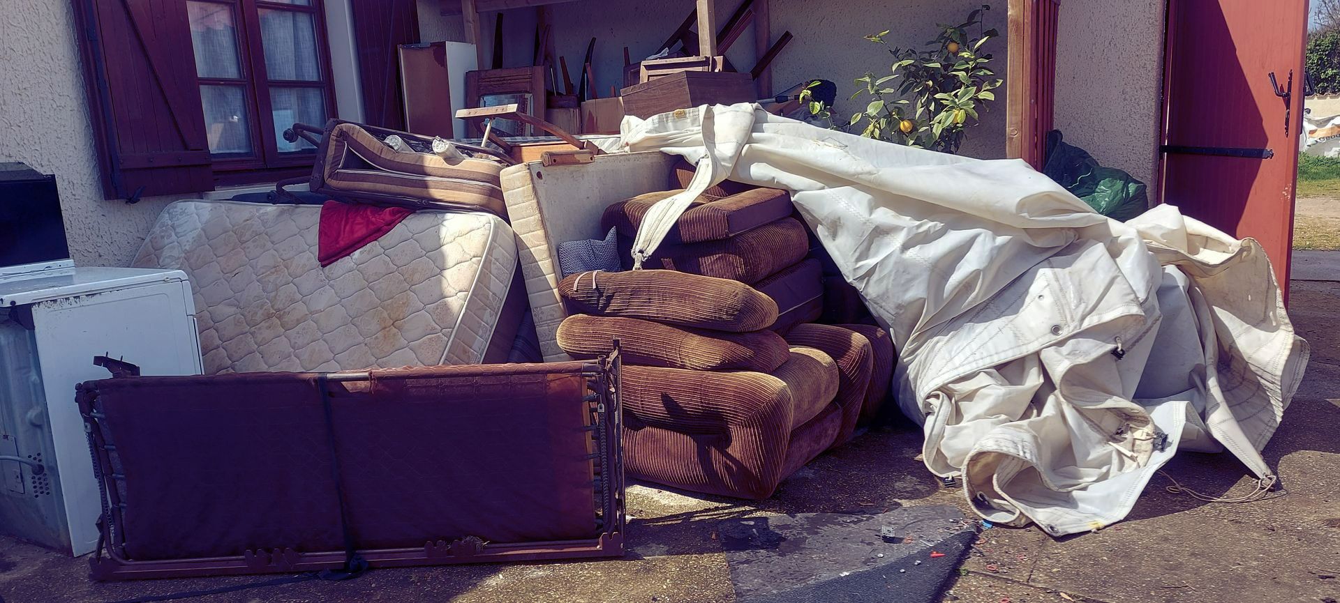 Pile d'objets, canapés, matelas devant une maison