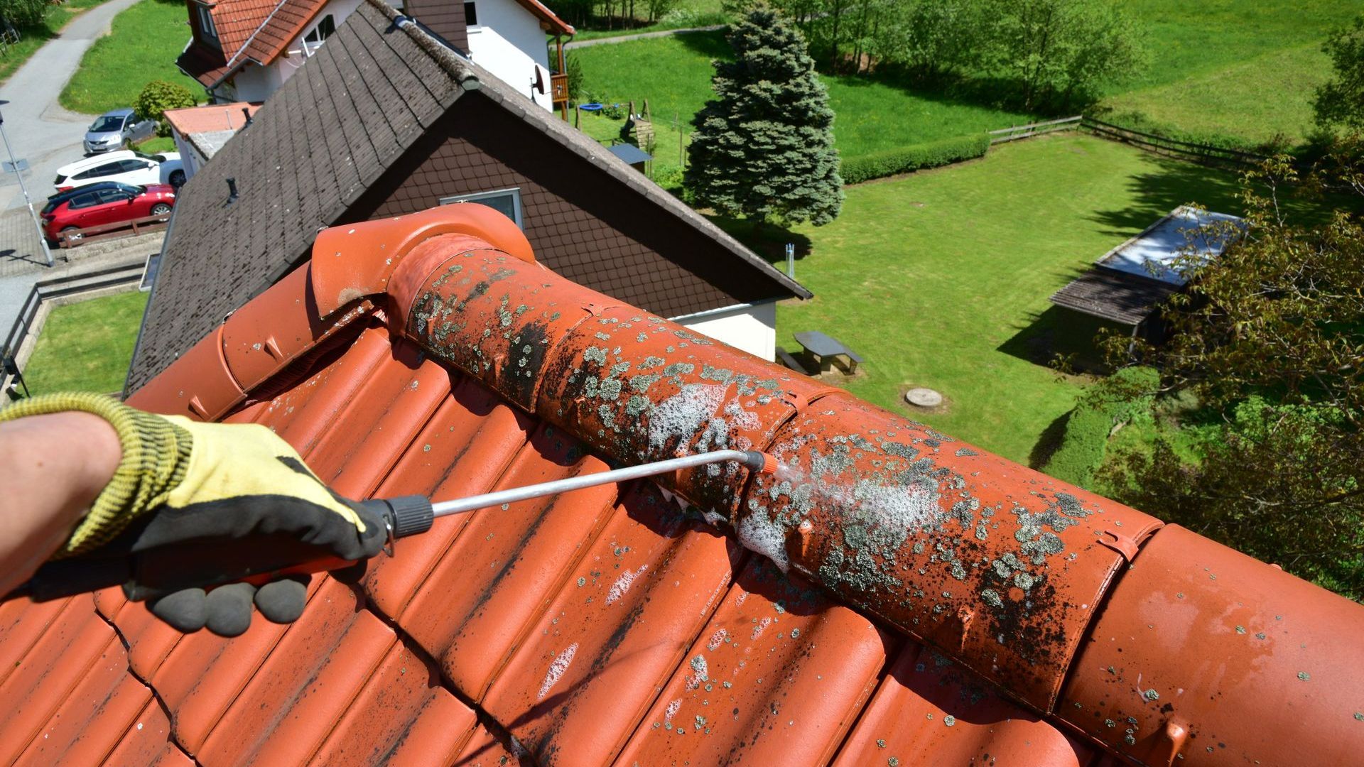 Un couvreur qui traite de la mousse sur des tuiles
