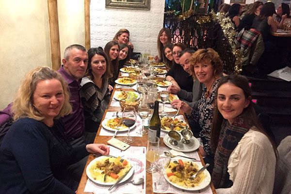 Un grupo de personas está sentada en una mesa larga comiendo comida.
