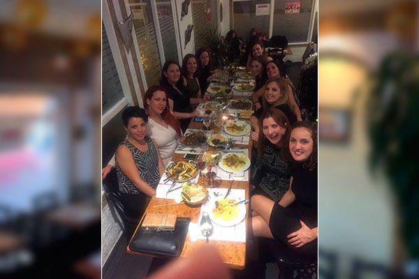 Un grupo de mujeres está sentada en una mesa larga con platos de comida.