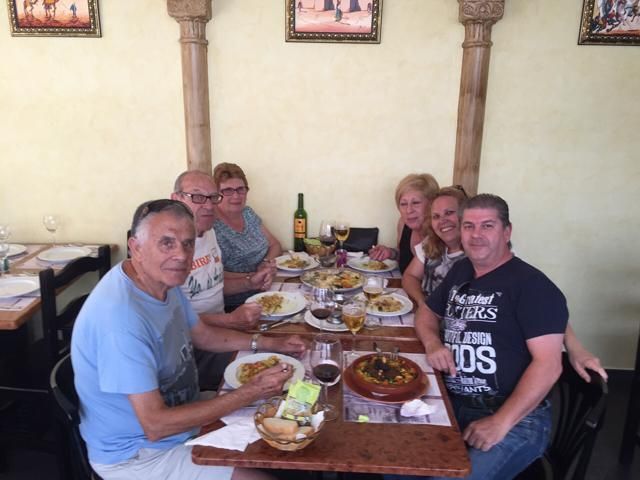 Un grupo de personas están sentadas alrededor de una mesa comiendo comida.
