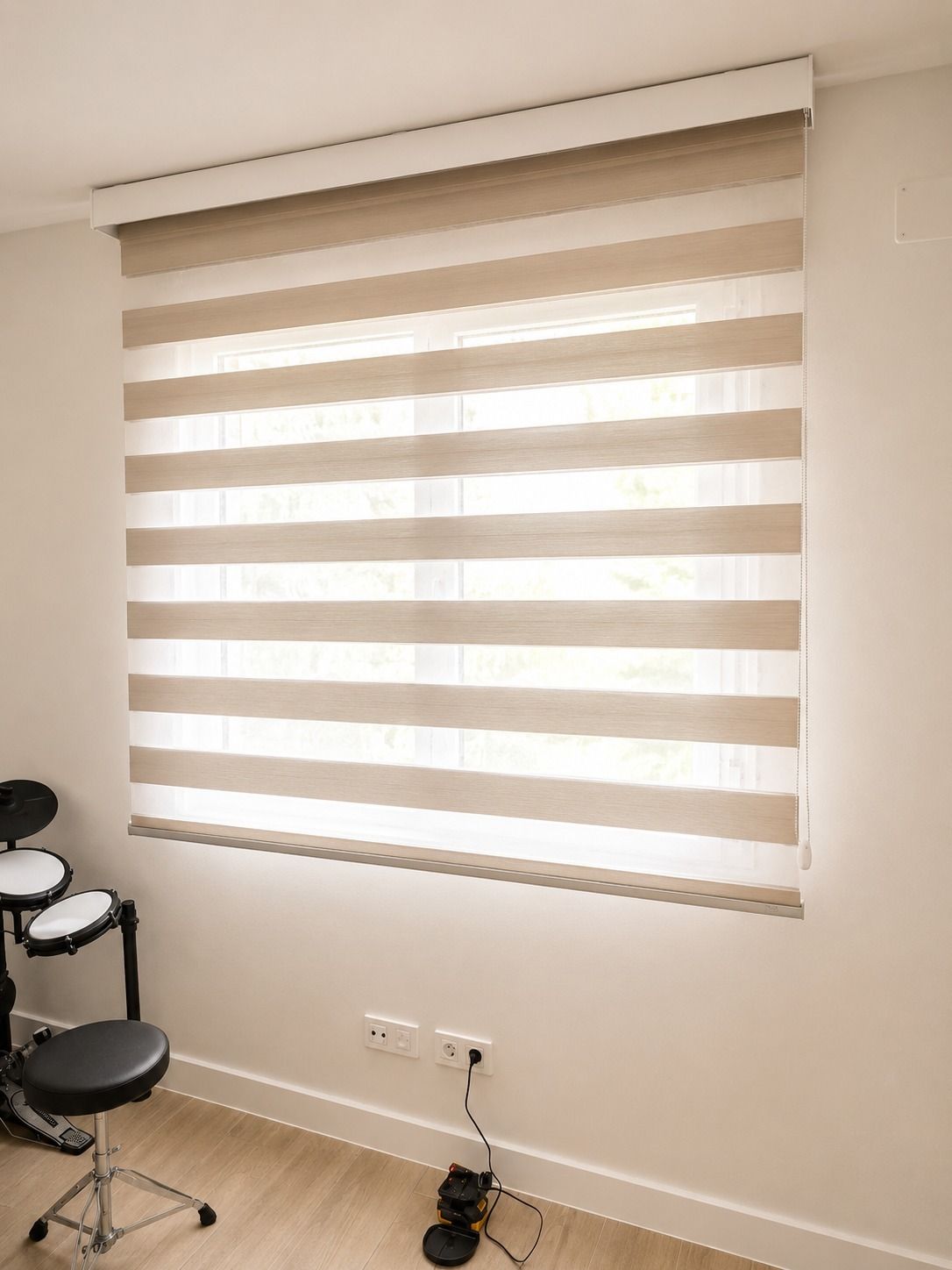 Acogedora habitación con cama, cabecero acolchado gris, lámpara de noche y persianas.