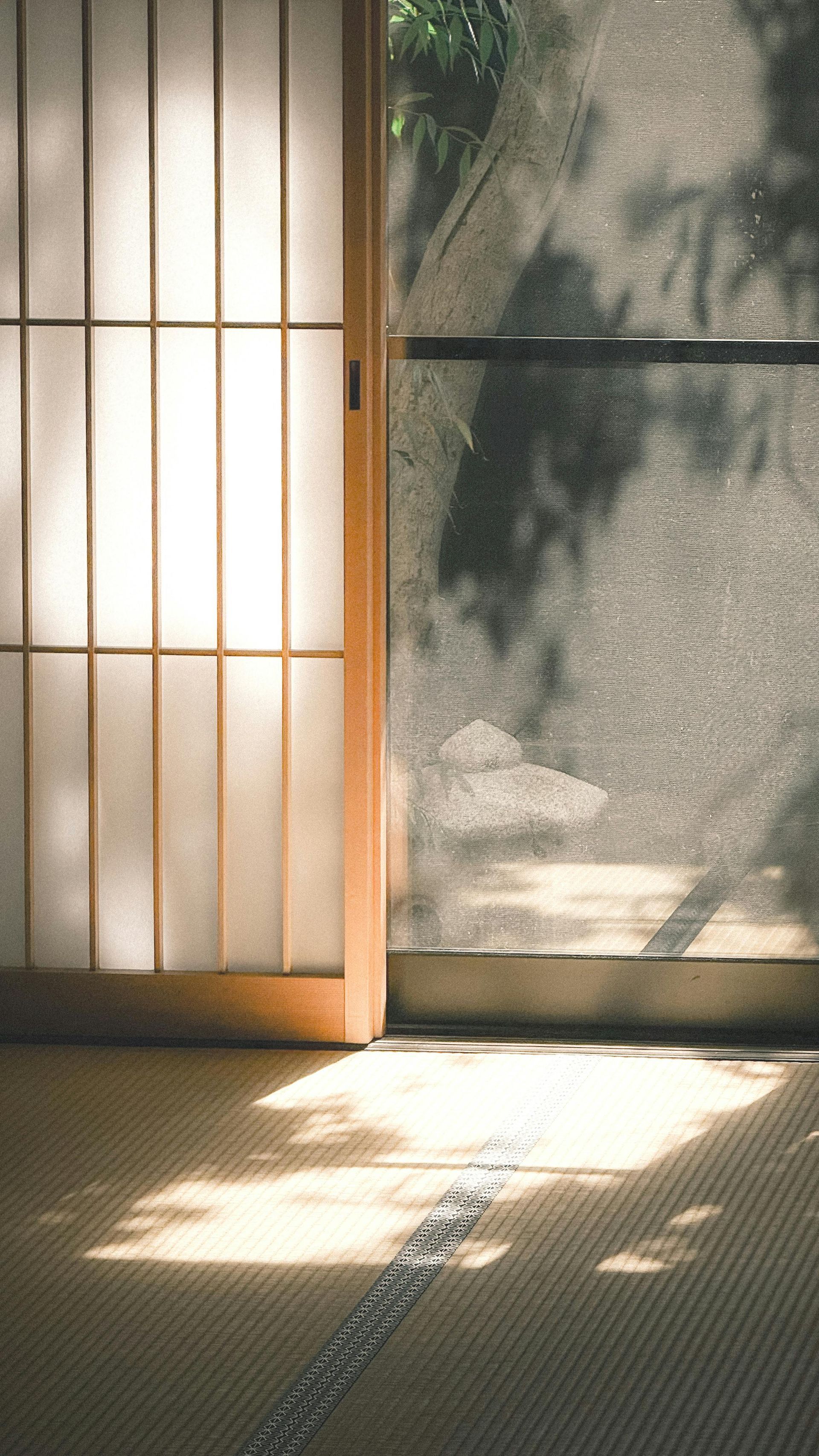 La luz del sol que entra por las puertas shoji proyecta cálidas sombras sobre el suelo de una habitación tatami.