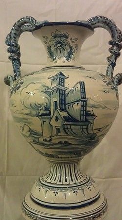 Un jarrón azul y blanco con una casa encima.