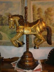 Un caballo de carrusel de madera está sentado encima de una mesa de madera.