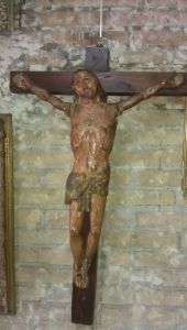 Una estatua de Jesús en una cruz está colgada en una pared de ladrillos.