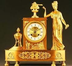 Un reloj de oro con una estatua de una mujer parada a su lado.