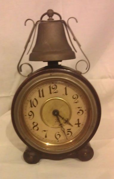 Un pequeño reloj con una campana encima.