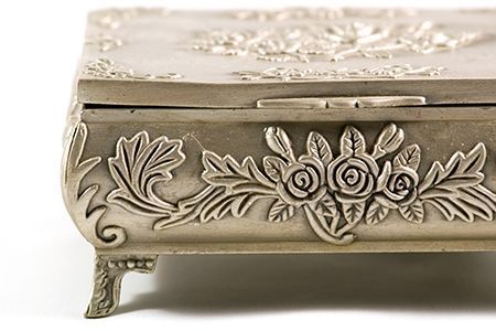 Un primer plano de una caja de plata con un diseño floral sobre un fondo blanco.
