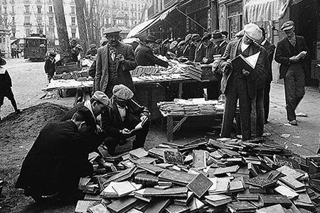 Un grupo de hombres está de pie alrededor de una pila de libros.