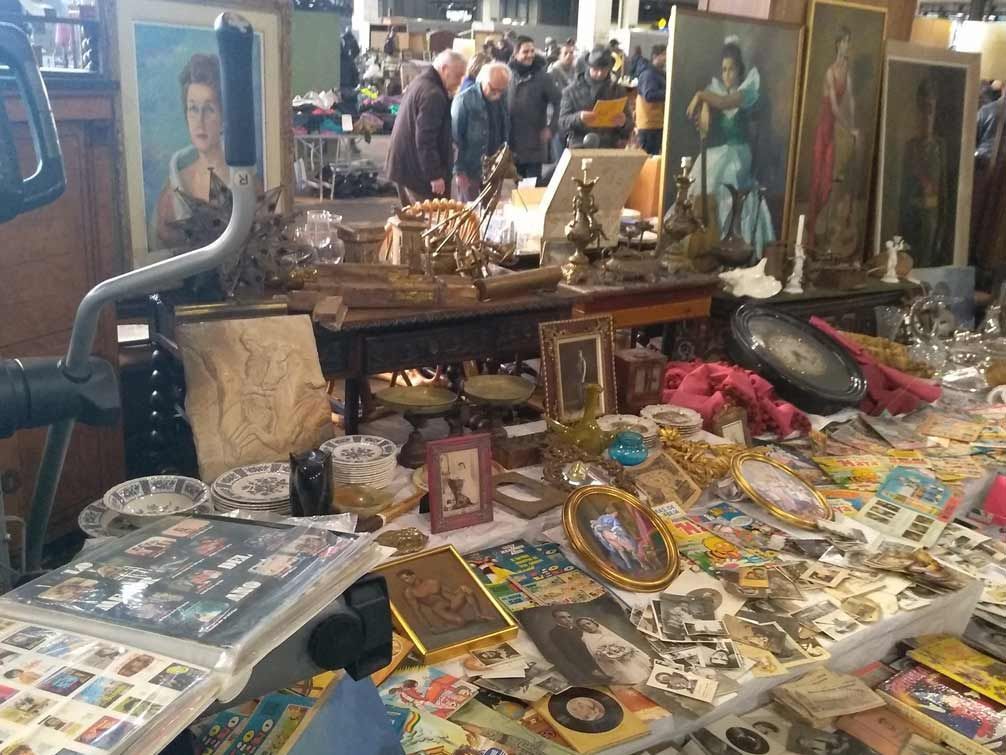 Una mesa con muchos objetos encima y una bicicleta al fondo.