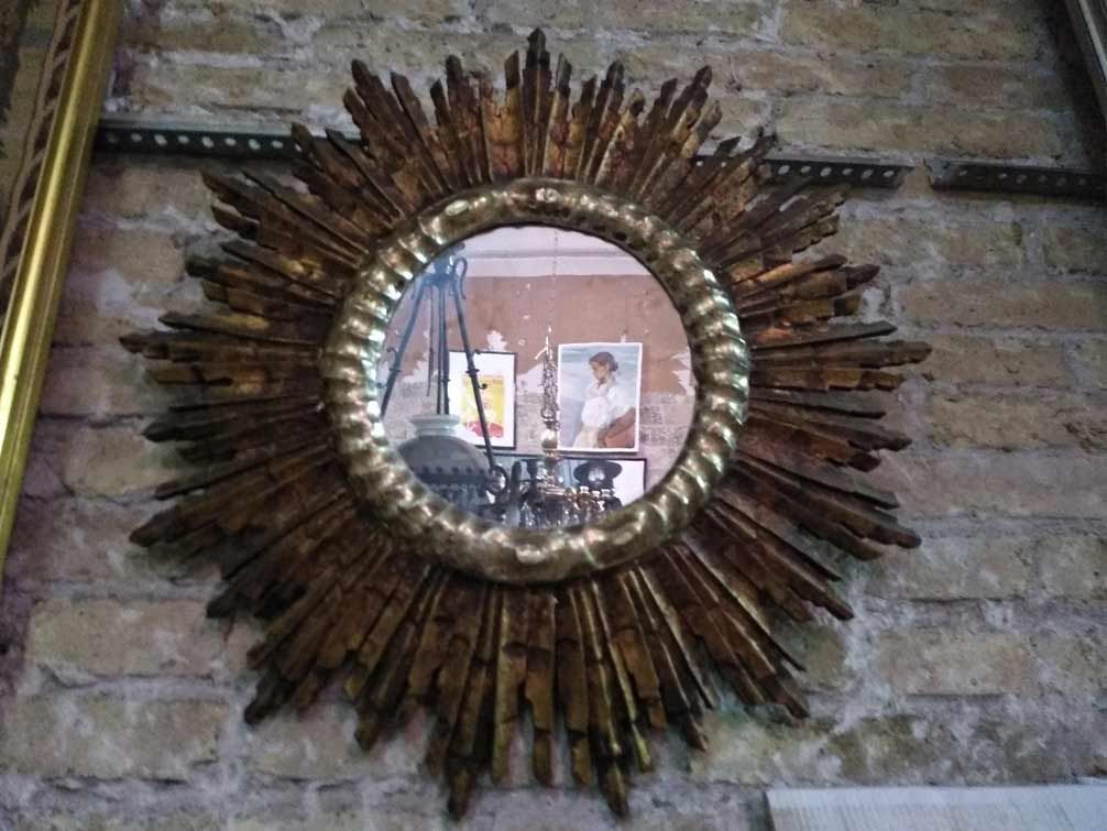 Un espejo redondo con marco de madera está colgado en una pared de ladrillos.