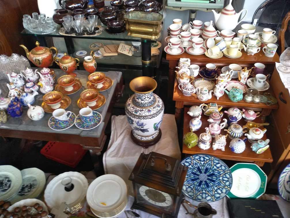 Una mesa llena de muchos platos, tazas y jarrones.