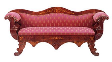 Un sofá de madera con un cojín de lunares rosas.