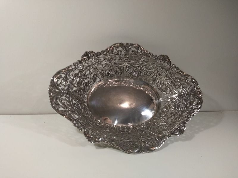 Un cuenco de plata reposa sobre una mesa blanca.