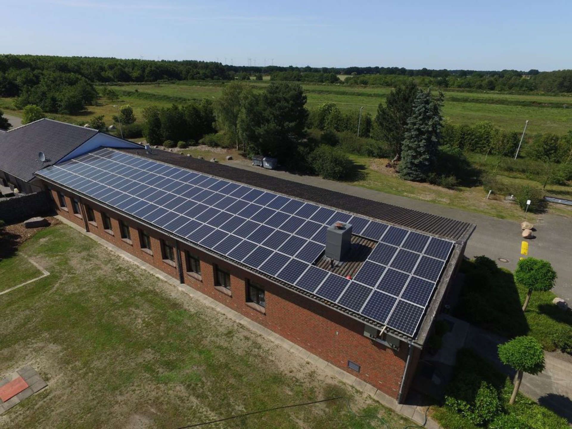 Eine Luftaufnahme eines Gebäudes mit einer Aufdachanlage auf dem Dach.