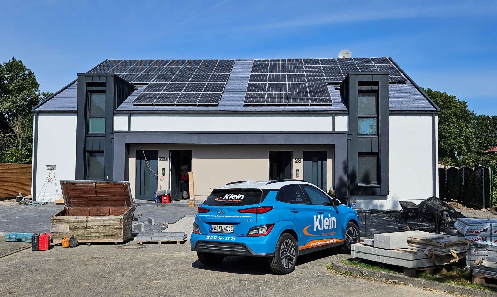 KNE Auto parkt vor einem Haus mit Solarzellen auf dem Dach.